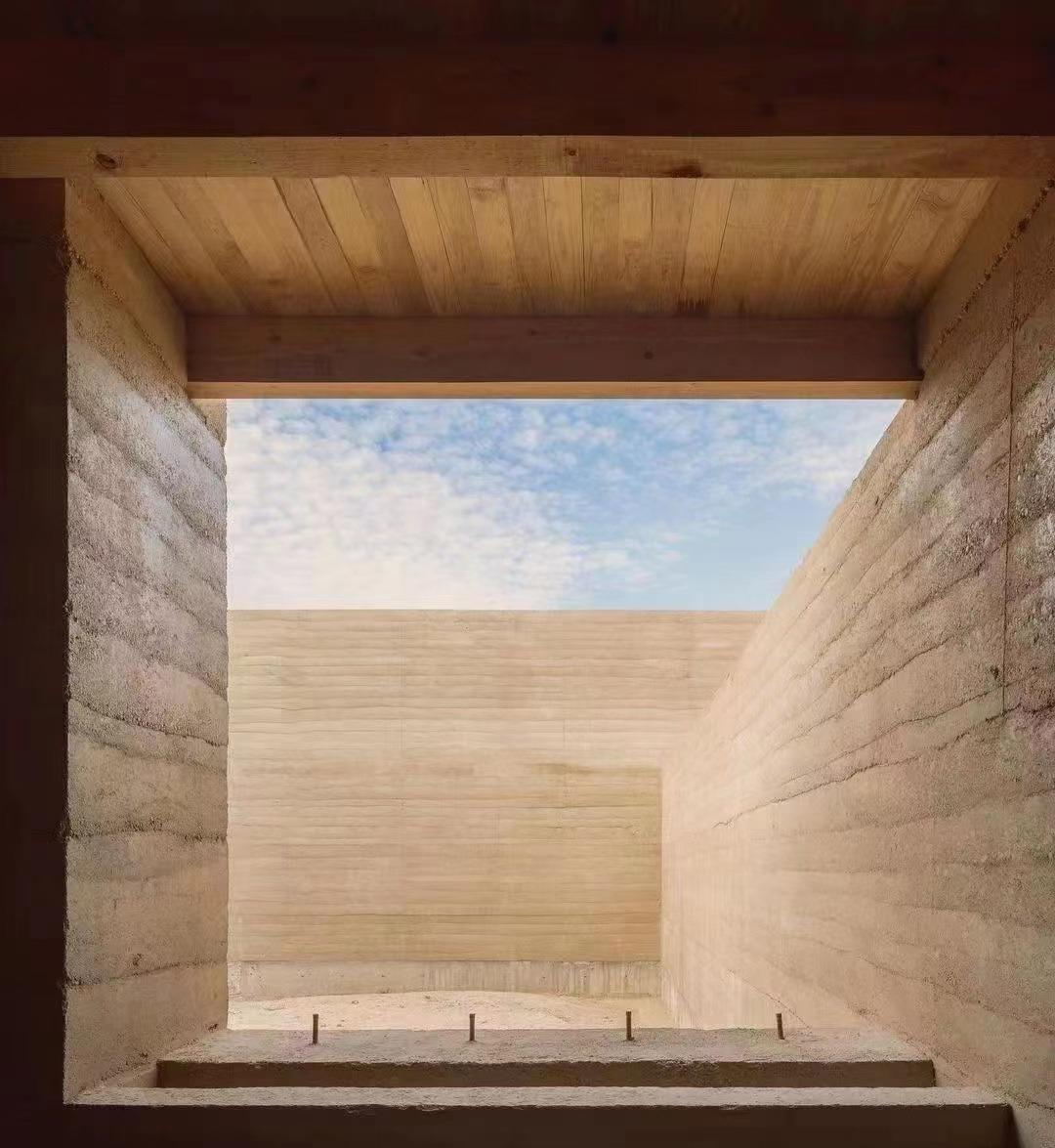 Rammed-earth courtyard walls framing the sky under a timber soffit