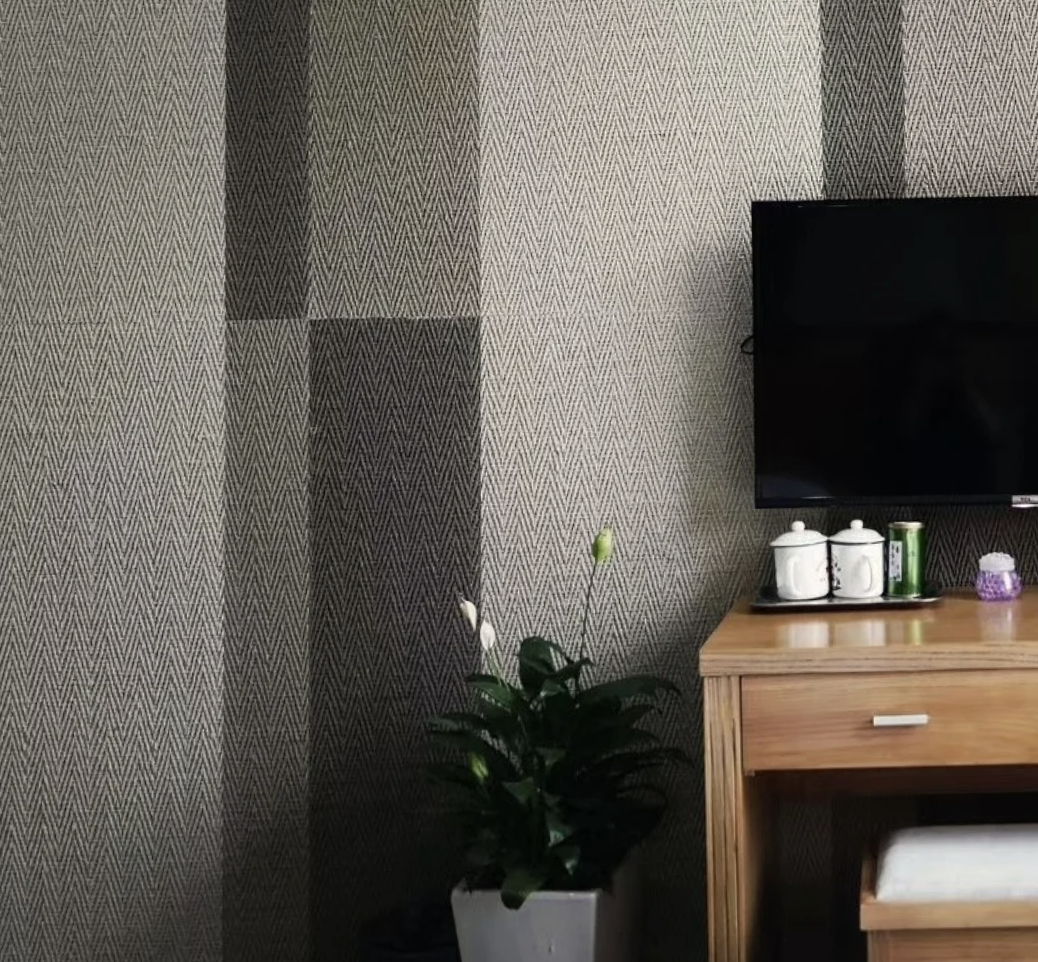 Guest room wall clad in fine herringbone-textured panels