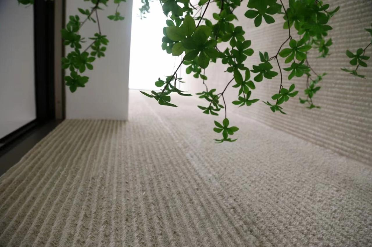 Fine linear-grooved stone surface with green foliage in the foreground